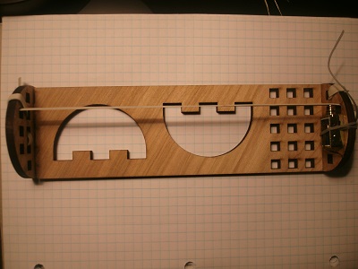 The laser-cut wave generator board.<br/><small>A linear actuator on one end vibrates the string, generating standing waves.</small>